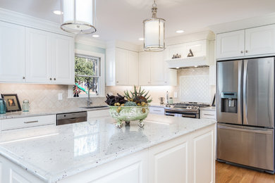 Photo of a mid-sized traditional l-shaped open plan kitchen in Raleigh with granite benchtops, ceramic splashback, an undermount sink, raised-panel cabinets, white cabinets, white splashback, stainless steel appliances, medium hardwood floors, with island, brown floor and white benchtop.