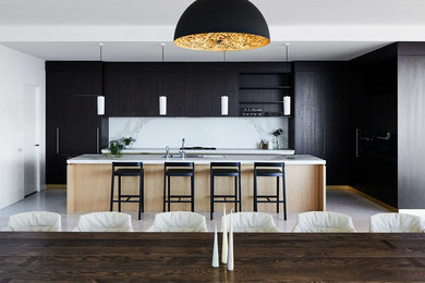 This is an example of a large contemporary single-wall eat-in kitchen in Melbourne with black cabinets, marble benchtops, white splashback, with island, a double-bowl sink, flat-panel cabinets, stainless steel appliances, ceramic floors, beige floor and white benchtop.