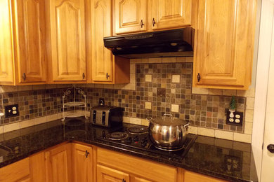 Inspiration for a large timeless u-shaped ceramic tile eat-in kitchen remodel in Charlotte with an undermount sink, raised-panel cabinets, light wood cabinets, granite countertops, multicolored backsplash, stone tile backsplash, black appliances and a peninsula