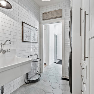 This is an example of a medium sized farmhouse single-wall separated utility room in Other with an utility sink, white cabinets, ceramic flooring, a stacked washer and dryer, recessed-panel cabinets and grey floors.