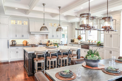Large cottage u-shaped medium tone wood floor and brown floor eat-in kitchen photo in Bridgeport with a farmhouse sink, recessed-panel cabinets, white cabinets, quartz countertops, white backsplash, subway tile backsplash, stainless steel appliances and an island