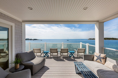 Inspiration for a large coastal backyard second story glass railing deck remodel in Boston with a roof extension