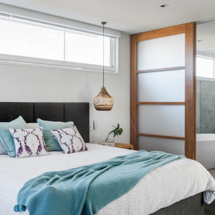 Maritimes Schlafzimmer mit weißer Wandfarbe, Teppichboden und schwarzem Boden in Sunshine Coast