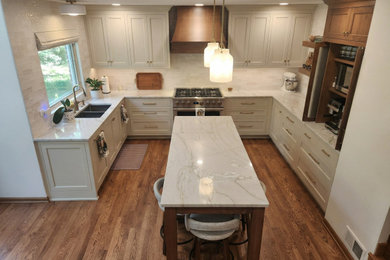 Mid-sized country u-shaped medium tone wood floor and brown floor kitchen photo in Chicago with an undermount sink, recessed-panel cabinets, beige cabinets, white backsplash, stainless steel appliances and white countertops