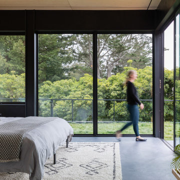Primary bedroom with floor-to-ceiling corner glazing, sliding glass door, and co