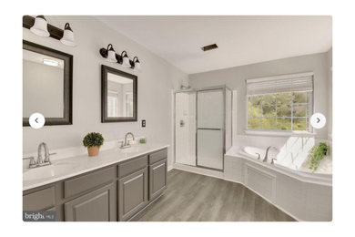 Example of a large trendy master white tile and ceramic tile laminate floor, gray floor, double-sink and tray ceiling bathroom design in DC Metro with furniture-like cabinets, gray cabinets, a two-piece toilet, white walls, an undermount sink, quartz countertops, white countertops and a built-in vanity