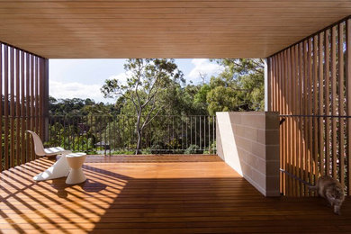 Design ideas for a mid-sized contemporary deck in Sydney with a roof extension and metal railing.