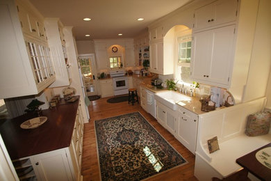 Enclosed kitchen - craftsman u-shaped medium tone wood floor enclosed kitchen idea in Milwaukee with a farmhouse sink, shaker cabinets, white cabinets, wood countertops, white appliances and a peninsula