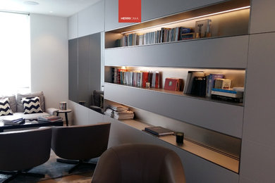 Immagine di un soggiorno contemporaneo chiuso con libreria, pareti bianche e TV a parete