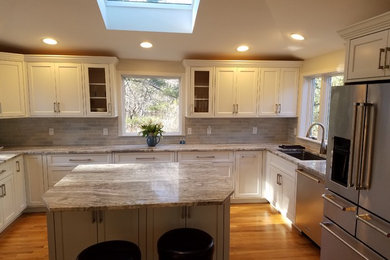 Inspiration for a mid-sized transitional u-shaped medium tone wood floor enclosed kitchen remodel in Boston with a single-bowl sink, recessed-panel cabinets, white cabinets, granite countertops, gray backsplash, ceramic backsplash, stainless steel appliances and an island