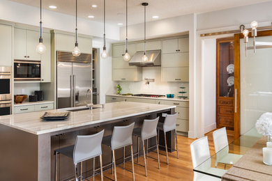 Mid-sized urban l-shaped dark wood floor and brown floor eat-in kitchen photo in Columbus with an undermount sink, flat-panel cabinets, green cabinets, marble countertops, white backsplash, porcelain backsplash, stainless steel appliances and an island