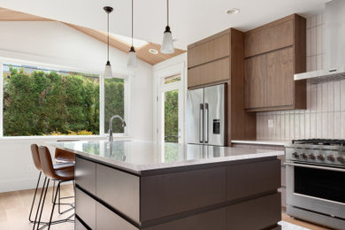 Example of a large minimalist u-shaped laminate floor, brown floor and vaulted ceiling eat-in kitchen design in Seattle with a single-bowl sink, flat-panel cabinets, medium tone wood cabinets, quartzite countertops, white backsplash, porcelain backsplash, stainless steel appliances, an island and white countertops