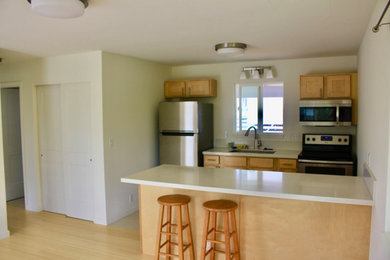 Example of a mid-sized beach style galley ceramic tile and beige floor open concept kitchen design in Hawaii with a double-bowl sink, recessed-panel cabinets, light wood cabinets, quartz countertops, white backsplash, stainless steel appliances, an island and white countertops