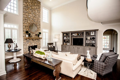 This is an example of a mid-sized transitional open concept living room with grey walls, dark hardwood floors, a standard fireplace, a stone fireplace surround and a built-in media wall.