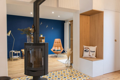 Réalisation d'une salle de séjour design ouverte avec une bibliothèque ou un coin lecture, un mur bleu, parquet clair, un poêle à bois, un sol jaune et éclairage.
