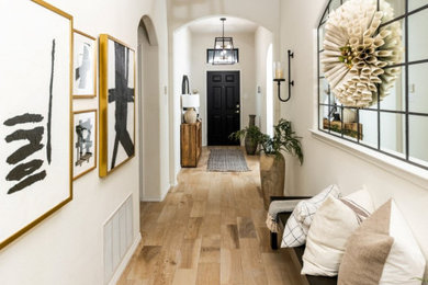 Example of a large country travertine floor and beige floor entryway design in Dallas with white walls and a black front door