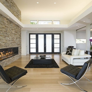 Idéer för att renovera ett funkis vardagsrum, med en bred öppen spis, en spiselkrans i sten och bambugolv