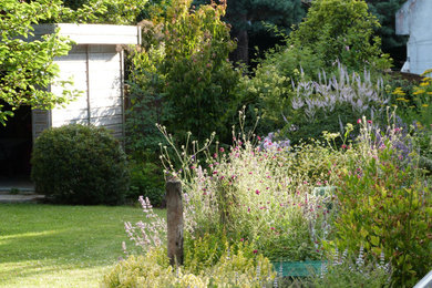 Réalisation d'un jardin arrière design avec un massif de fleurs et une exposition ensoleillée.