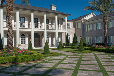 Inspiration for an expansive traditional two-storey beige exterior in Orlando with stone veneer and a hip roof.