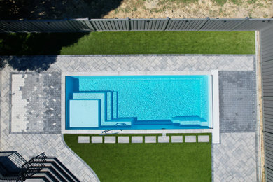 Imagen de piscina moderna en patio trasero con paisajismo de piscina y adoquines de ladrillo