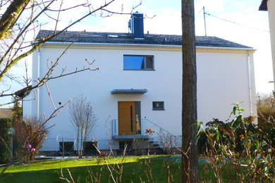Zweistöckige Moderne Doppelhaushälfte mit Putzfassade, Satteldach, Ziegeldach und grauem Dach in München