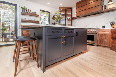 Foto på ett mellanstort funkis flerfärgad kök och matrum, med skåp i shakerstil, skåp i mörkt trä, marmorbänkskiva, vitt stänkskydd, rostfria vitvaror, ljust trägolv, en köksö och brunt golv