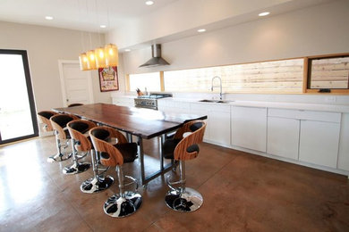 Example of a large trendy single-wall concrete floor eat-in kitchen design in Denver with a double-bowl sink, flat-panel cabinets, white cabinets and stainless steel appliances