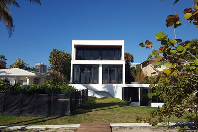 Large modern three-storey concrete white house exterior in Miami with a flat roof.