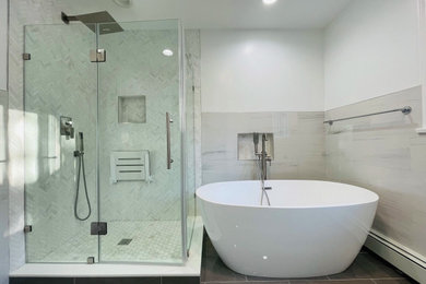 Example of a large minimalist master gray tile and matchstick tile ceramic tile, gray floor, double-sink and vaulted ceiling bathroom design in New York with shaker cabinets, gray cabinets, a one-piece toilet, white walls, an undermount sink, granite countertops, a hinged shower door, white countertops and a freestanding vanity