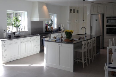 This is an example of an expansive traditional open plan kitchen in Copenhagen with raised-panel cabinets, white cabinets and with island.