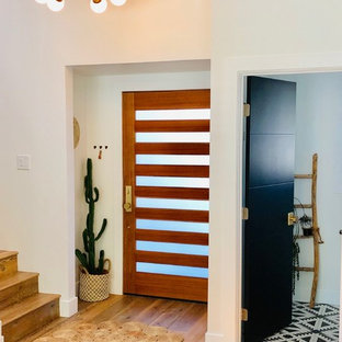 Inspiration för stora eklektiska ingångspartier, med vita väggar, laminatgolv, en enkeldörr, mellanmörk trädörr och brunt golv