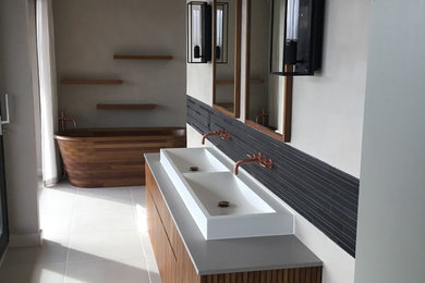 Design ideas for a large modern family bathroom in Gloucestershire with grey cabinets, a freestanding bath, a walk-in shower, a one-piece toilet, grey tiles, beige walls, a trough sink, beige floors and grey worktops.