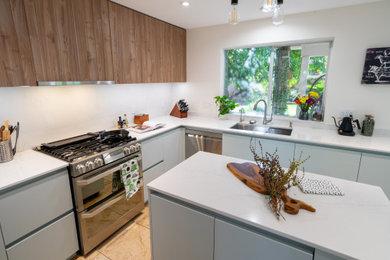 Small trendy l-shaped limestone floor and beige floor eat-in kitchen photo in Phoenix with a drop-in sink, flat-panel cabinets, light wood cabinets, quartz countertops, white backsplash, quartz backsplash, stainless steel appliances, an island and white countertops