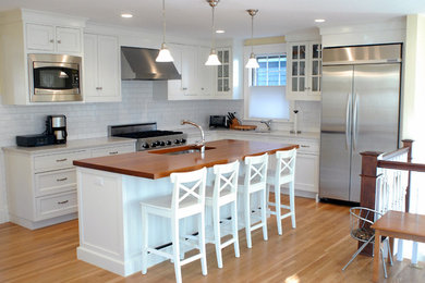 Eat-in kitchen - traditional l-shaped light wood floor eat-in kitchen idea in Boston with an undermount sink, beaded inset cabinets, white cabinets, quartz countertops, white backsplash, subway tile backsplash, stainless steel appliances and an island