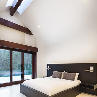 Idée de décoration pour une grande chambre parentale design avec un mur blanc, une cheminée standard, un manteau de cheminée en plâtre et un sol blanc.