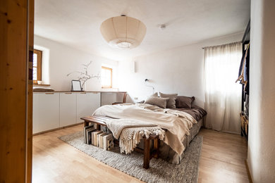 Mittelgroßes Skandinavisches Hauptschlafzimmer mit weißer Wandfarbe, Laminat, braunem Boden und Tapetenwänden in München