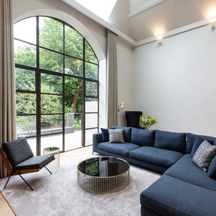 Inredning av ett modernt mellanstort loftrum, med vita väggar, ljust trägolv och beiget golv