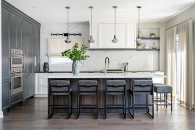 Large transitional l-shaped medium tone wood floor and brown floor eat-in kitchen photo in Toronto with a double-bowl sink, shaker cabinets, white backsplash, stone slab backsplash, stainless steel appliances and an island