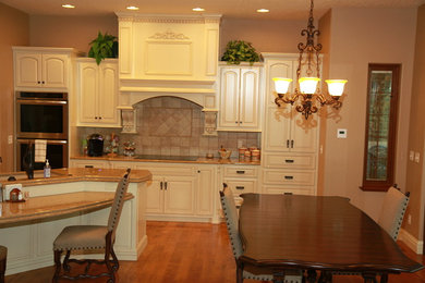 Mid-sized elegant l-shaped medium tone wood floor open concept kitchen photo in Wichita with raised-panel cabinets, quartz countertops, an island, white cabinets, ceramic backsplash, stainless steel appliances, an undermount sink and beige backsplash