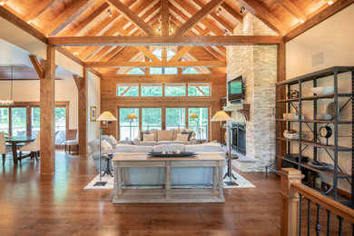 Living room - rustic open concept medium tone wood floor and brown floor living room idea in Other with a hanging fireplace, a stone fireplace, a wall-mounted tv and white walls
