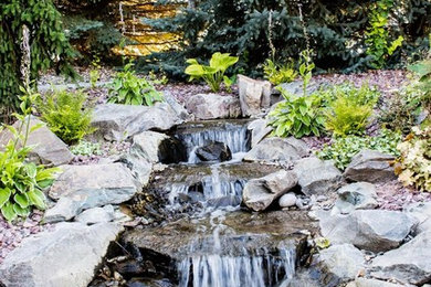 Photo of a mid-sized traditional full sun hillside gravel pond in Other for spring.