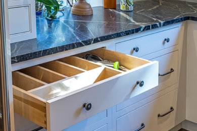 Example of a huge transitional u-shaped cork floor and brown floor enclosed kitchen design in Philadelphia with an undermount sink, flat-panel cabinets, white cabinets, soapstone countertops, green backsplash, ceramic backsplash, stainless steel appliances, a peninsula and multicolored countertops