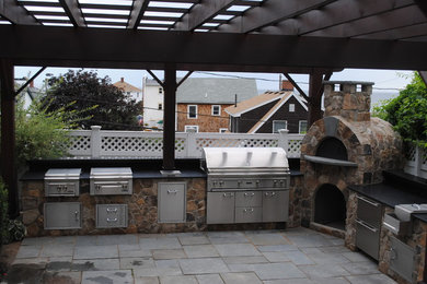 Inspiration for a patio in Boston with an outdoor kitchen, brick pavers and a pergola.