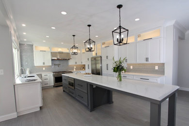 Kitchen - large transitional u-shaped light wood floor and gray floor kitchen idea in Baltimore with an undermount sink, shaker cabinets, white cabinets, quartz countertops, gray backsplash, ceramic backsplash, stainless steel appliances, an island and white countertops