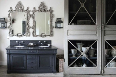 This is an example of a medium sized traditional bathroom in Surrey with recessed-panel cabinets, blue cabinets, beige walls, a submerged sink and grey floors.