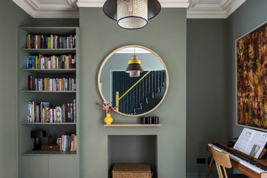 Foto di una sala da pranzo aperta verso il soggiorno contemporanea con pareti verdi e parquet chiaro