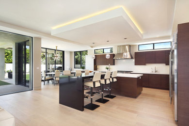 Example of a large minimalist light wood floor, beige floor and tray ceiling eat-in kitchen design in Los Angeles with an undermount sink, flat-panel cabinets, quartzite countertops, white backsplash, stone slab backsplash, stainless steel appliances, an island, white countertops and brown cabinets