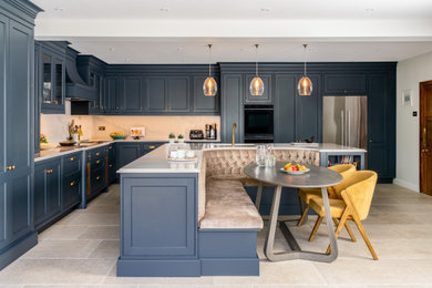 Photo of a large classic kitchen in Sussex with shaker cabinets, blue cabinets, quartz worktops, black appliances, porcelain flooring and an island.