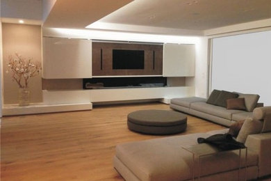 Imagen de cine en casa abierto grande con paredes beige, suelo de madera clara, pared multimedia y suelo marrón