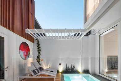 This is an example of a small contemporary backyard pool in Melbourne with a hot tub and decking.